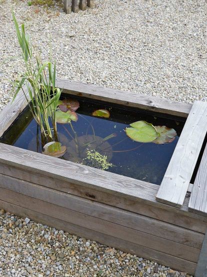 Holzbrunnen mit Wasserbepflanzung, auch zum Wässern von Weidenruten erstellt, wird jährlich mit Topfpflanzen begrünt